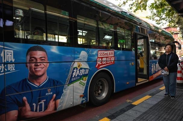Autobús en China con publicidad de Mbappé para la bebida Bu Shui La de Dongpeng