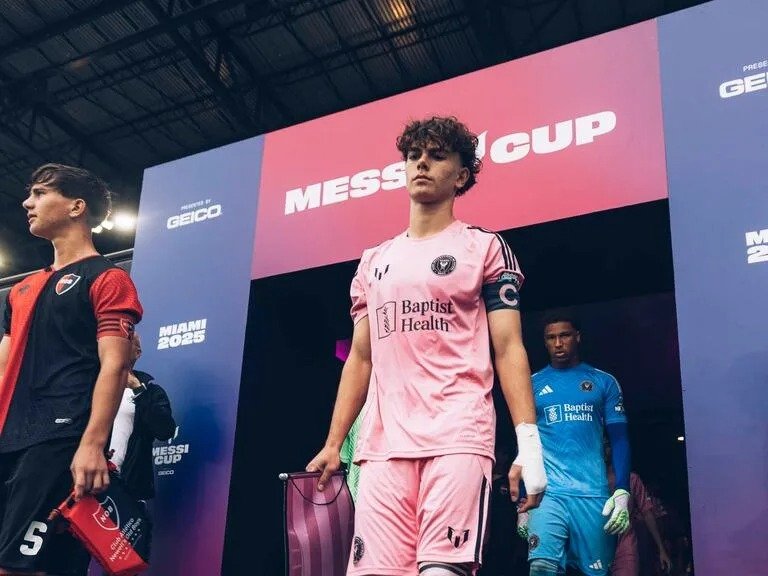 Inter Miami U-16 players, in pink uniforms, and Newell's Old Boys players walk onto the field under the Messi Cup arch