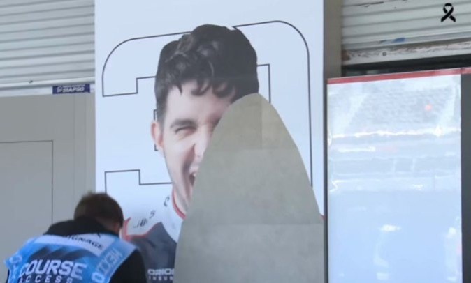 A worker covers a poster of Esteban Ocon at the circuit