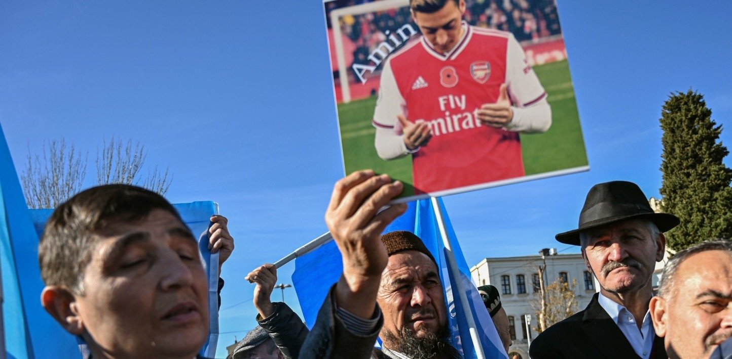 Manifestantes uigures sostienen un cartel con la imagen de Mesut Özil con la camiseta del Arsenal